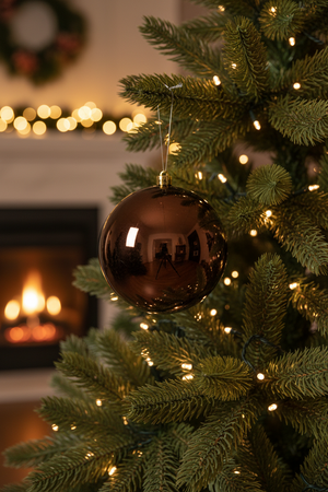 Kissmas Statement Espresso Bauble 14cm hanging on the side of a full lush Christmas tree with fairy lights